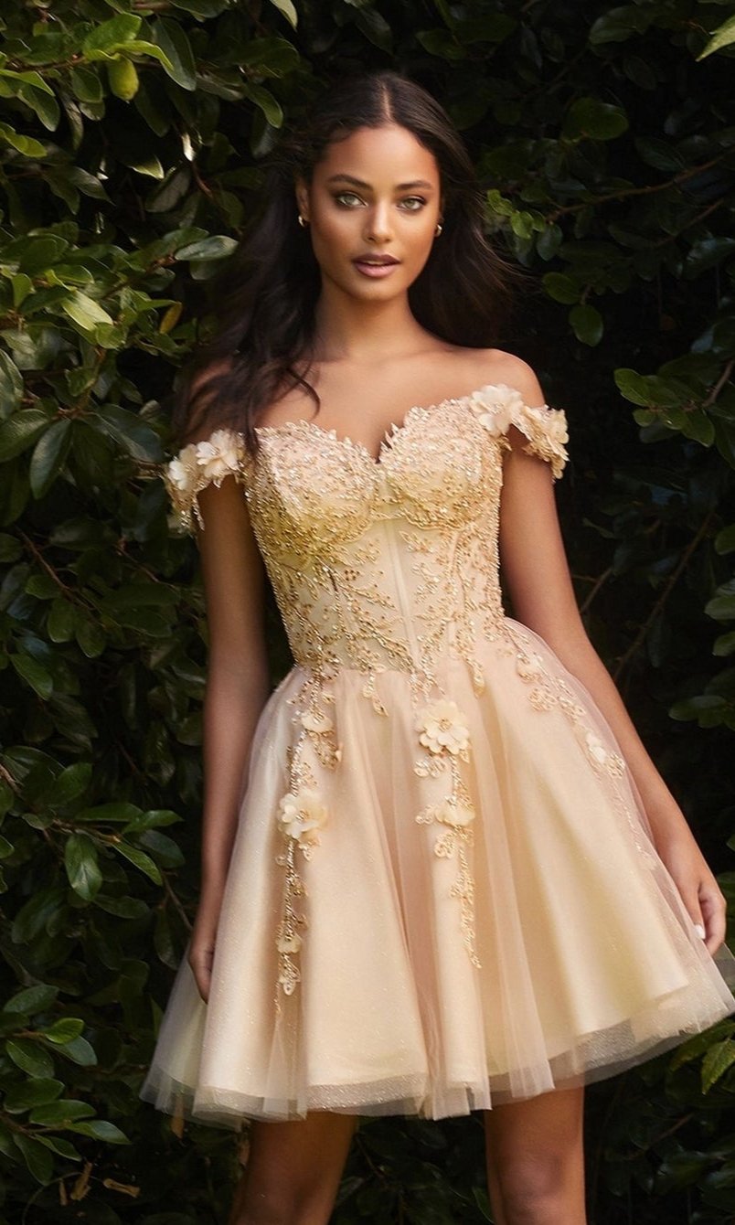 A woman stands before green foliage in the Off-Shoulder Short Floral Homecoming Dress CD0194, featuring a fitted off-the-shoulder bodice, A-line skirt, and 3D floral embellishments.